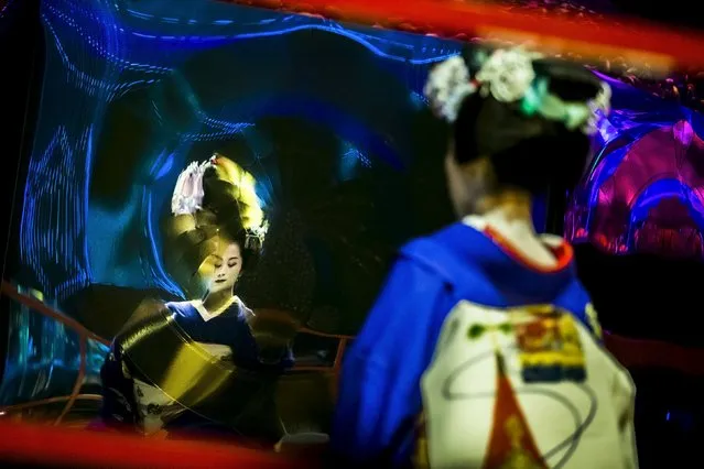 A Maiko, an apprentice geisha, is reflected in a warped mirror as she performs a traditional dance in front of a tank with goldfish at the Art Aquarium exhibition in Tokyo July 27, 2015. (Photo by Thomas Peter/Reuters)