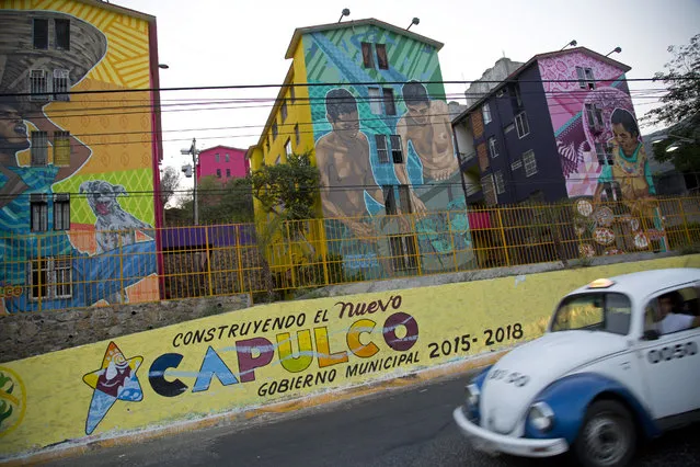 In this May 11, 2016 photo, a taxi drives past the Cuauhtemoc Housing Unit and a municipal sign with a message that reads in Spanish; “Building the new Acapulco” in Acapulco, Mexico. (Photo by Enric Marti/AP Photo)