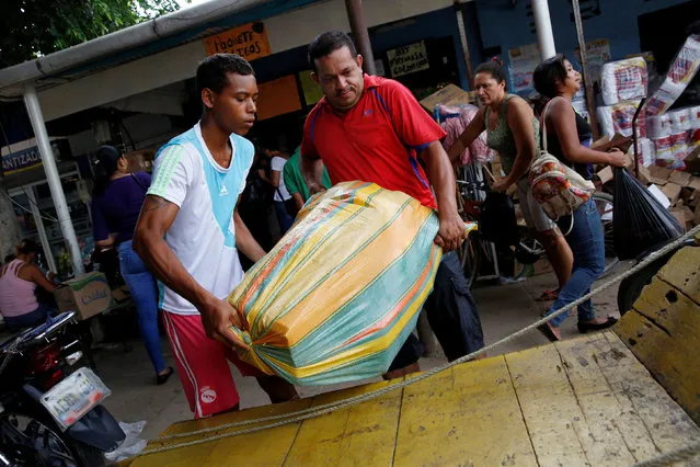 Men carry a bag filled with staple items in front of a store in Puerto Santander, Colombia, June 3, 2016. (Photo by Carlos Garcia Rawlins/Reuters)