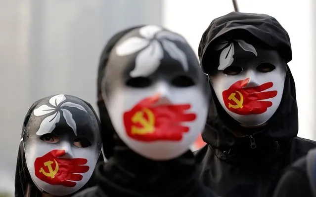People wearing masks stand during a rally to show support for Uighurs and their fight for human rights in Hong Kong, Sunday, December 22, 2019. (Photo by Lee Jin-man/AP Photo)