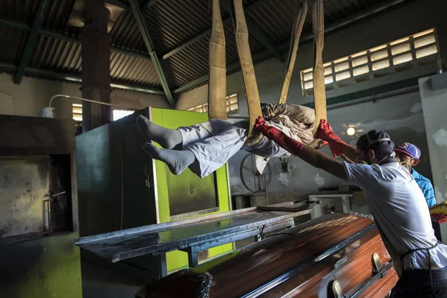 Cemetery workers lift a corpse from a coffin to a metal plate as they prepare the body for cremation at a cemetery in Maracaibo, Venezuela, November 27, 2019. Some overcome the financial burden of a relative's death by renting caskets, a cheaper option than buying one. (Photo by Rodrigo Abd/AP Photo)