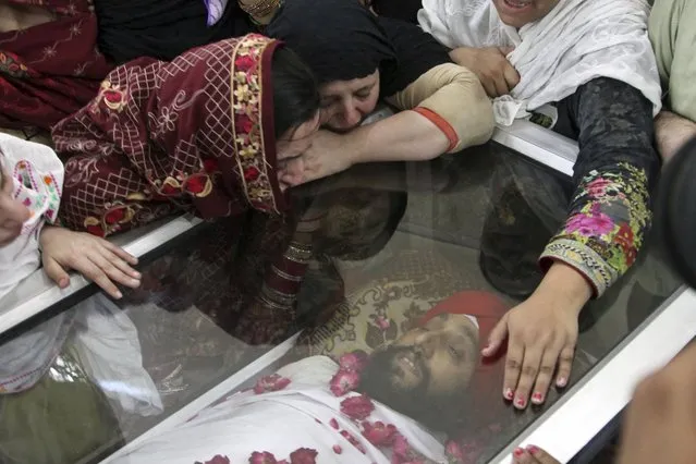 Pakistani Sikh mourners gather around the body of a Sikh who was killed by gunmen in Peshawar, Pakistan, Sunday, May 15, 2022. Police officer Ejaz Khan said gunmen on a motorcycle opened fire on two members of the minority Sikh community in a bazaar in the Peshawar suburb of Sarband. (Photo by Mohammad Zubair/AP Photo)