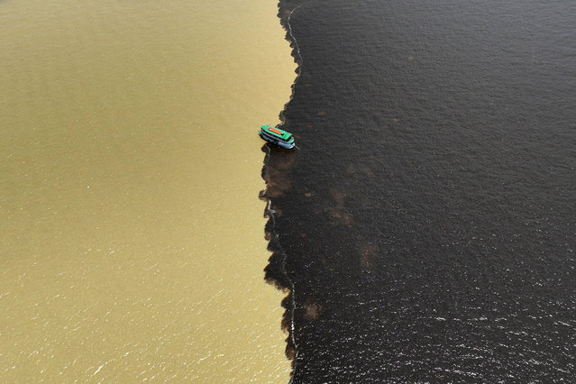 A drone view shows a boat navigating at the confluence point between the Rio Negro and the Rio Solimoes, to continue into the Amazon river near Manaus, Amazonas state, Brazil on September 21, 2024. (Photo by Jorge Silva/Reuters)