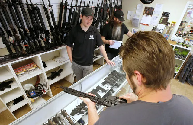 A prospective buyer examines an AR-15 as salesman Ryan Martinex watches at the “Ready Gunner” gun store in Provo, Utah, U.S., June 21, 2016. (Photo by George Frey/Reuters)