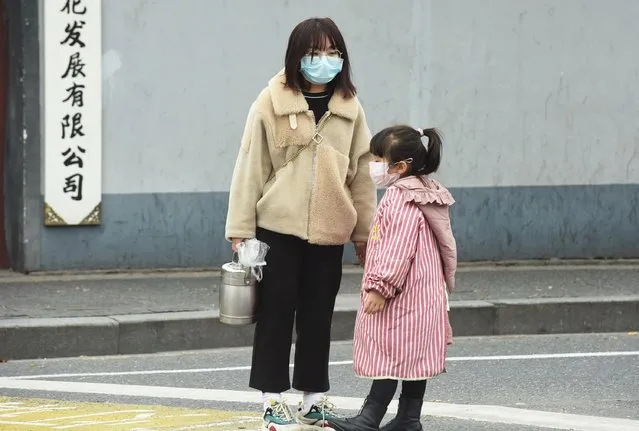 A woman and a child wearing masks stand on a street in Hangzhou, Zhejiang province, China on January 21, 2020. (Photo by Reuters/China Daily)
