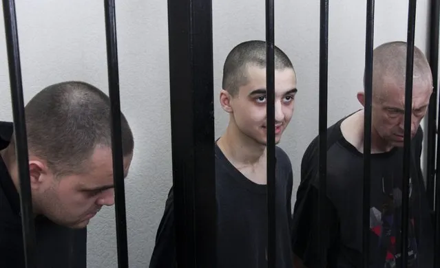 Two British citizens Aiden Aslin, left, and Shaun Pinner, right, and Moroccan Saaudun Brahim, center, sit behind bars in a courtroom in Donetsk, in the territory which is under the Government of the Donetsk People's Republic control, eastern Ukraine, Thursday, June 9, 2022. The two British citizens and a Moroccan have been sentenced to death by pro-Moscow rebels in eastern Ukraine for fighting on Ukraine's side. The three men fought alongside Ukrainian troops and surrendered to Russian forces weeks ago. (Photo by AP Photo/Stringer)