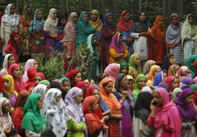 Kashmiri villagers watch the funeral procession of a civilian, Bilal Ahmad Bhat, at Padgampora village in Pulwama district, south of Srinagar, August 12, 2015. Bhat was killed on Tuesday after Indian security forces allegedly opened fire on protesters who were protesting against the killings of two suspected militants in an encounter with Indian security forces, local media reported. (Photo by Danish Ismail/Reuters)
