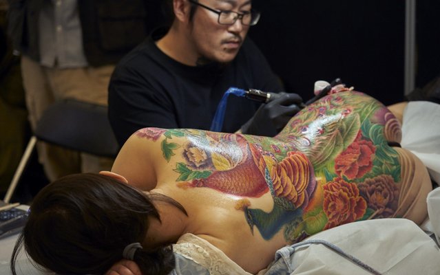 A tattooist works on a tattoo with oriental designs in the course the International Tattoo Convention on October 25, 2019 in Amsterdam, Netherlands. Today begins the 15th edition of the Amsterdam International Tattoo Convention. During the weekend tattooers from all over the world will show their new designs with which they will compete in a contest that includes all styles and categories. (Photo by Nacho Calonge/Getty Images)