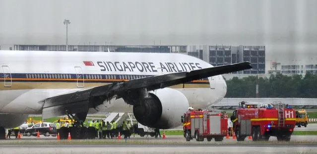 A burnt wing of a Singapore Airlines Boeing 777 plane is seen as the plane sits on the runway after an emergency landing at the Changi Airport in Singapore, 27 June 2016. On 27 June Singapore Airlines flight SQ 368 bound for Milan, Italy was forced to turn back soon after takeoff due to an engine oil warning message. Soon after landing back at Changi Airport, one of the plane's engines caught fire. The blaze was extinguished within minutes and no injuries or fatalities were reported. The passengers and crew disembarked safely. (Photo by Lim Yaohui/EPA)