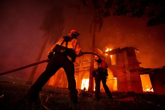 Firefighters work to put out a fire that has consumed a house by the Coastal Fire in Laguna Niguel, California, USA, 11 May 2022. Latest r​eports state that the 200 acre fire has destroyed more than a dozen homes. (Photo by Etienne Laurent/EPA/EFE)