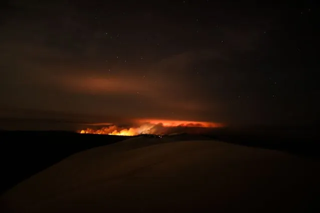 Wild fires rage near the Pilat sand dunes, Dune de Pilat, at La Teste-de-Buch, southwest France early on July 18, 2022. France was on high alert on July 18, 2022, as the peak of a punishing heatwave gripped the country, while wildfires raging in parts of southwest Europe showed no sign of abating. Forecasters have put 15 French departments on the highest state of alert for extreme temperatures as neighbouring Britain was poised to set new heat records this coming week. (Photo by Thibaud Moritz/AFP Photo)