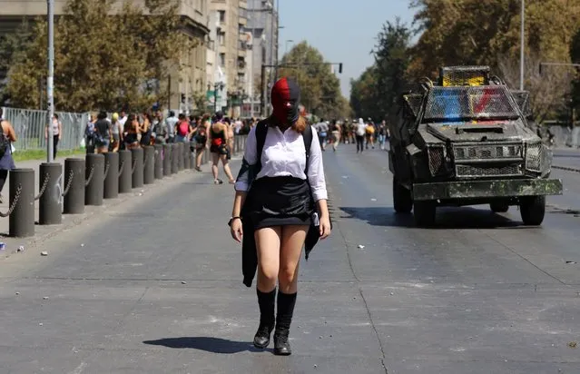 A woman walks next to riot police vehicle during a women's strike as part of International Women's Day activities in Santiago, Chile on March 9, 2020. (Photo by Sofia Yanjari/Reuters)