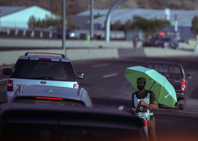 A Saudi traffic policeman raises his umbrella at a check point in the Arafat tent camp, in the Saudi Arabia's holy city of Mecca, Tuesday, July 5, 2022. Saudi Arabia is expected to receive one million Muslims to attend Hajj pilgrimage, which will begin on July 7, after two years of limiting the numbers because coronavirus pandemic. (Photo by Amr Nabil/AP Photo)