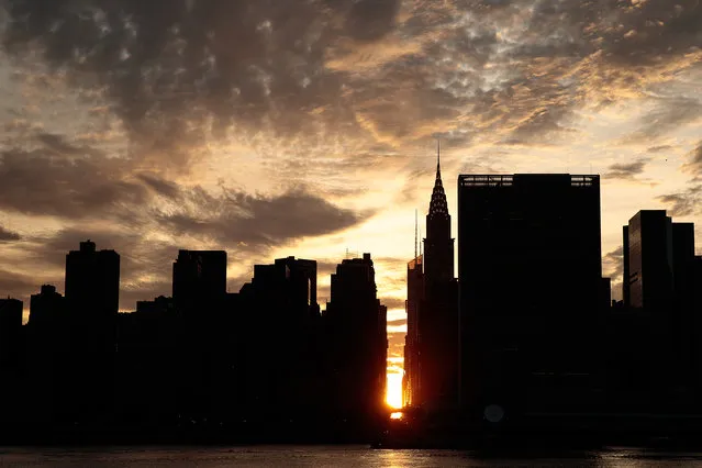 A view of the “Manhattanhenge” sunset from Hunters Point South Park, July 11, 2016 in the Queens borough of New York City. “Manhattanhenge” is created when the setting sun aligns with the city's street grid. (Photo by Drew Angerer/Getty Images)