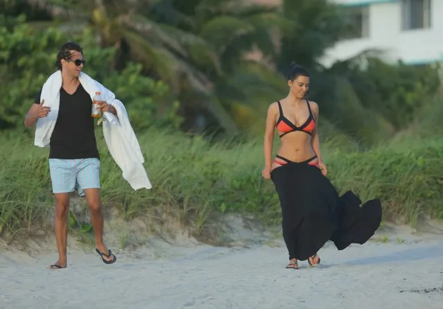 Kim Kardashian surfs up an impressive sight as she wanders along a Miami beach in a colourful bikini on August 4, 2012. The reality TV star looked stunning as she wandered barefoot along the shore in the black and orange two-piece