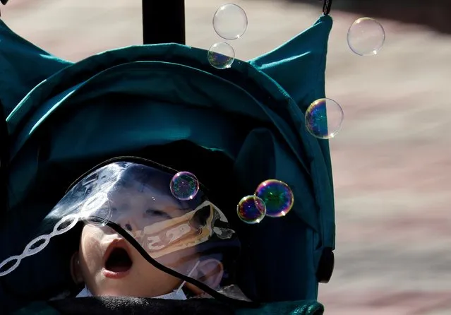 A boy wearing a hat with a protective screen, following an outbreak of coronavirus disease (COVID-19), blows soap bubbles at a park in Daegu, South Korea, March 12, 2020. (Photo by Kim Kyung-Hoon/Reuters)