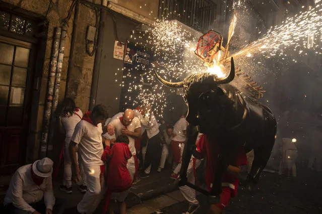 People and children are chased by the “Toro de Fuego” (flaming bull) as it runs through the streets during the opening day or “Chupinazo” of the San Fermin Running of the Bulls fiesta on July 06, 2022 in Pamplona, Spain. The iconic Spanish festival has resumed in earnest this year after being twice cancelled due to Covid-19. (Photo by Pablo Blazquez Dominguez/Getty Images)