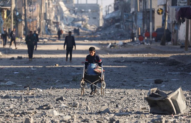 A Palestinian boy pushes a gas cylinder and other objects placed on a wheelchair, amid rubble at the site of an Israeli strike on a house, amid the Israel-Hamas conflict, in Nuseirat in the central Gaza Strip on December 1, 2024. (Photo by Ramadan Abed/Reuters)