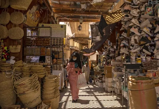 A woman walks past shops in the ancient Moroccan city of Fez on June 8, 2022. Today, Fez serves as a monument to a highpoint of Islamic civilisation, the 13th and 14th centuries when Muslim rulers governed from Morocco to western China. (Photo by Fadel Senna/AFP Photo)