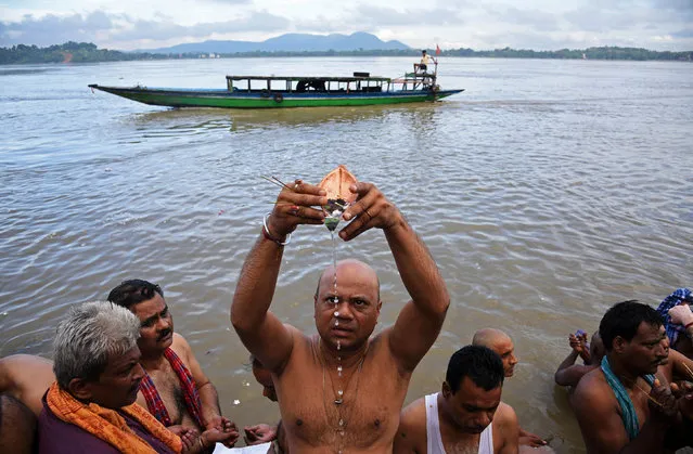 A Hindu man performs Tarpana, a religious ritual, on the banks of the river Brahmaputra to honour the souls of his departed ancestors during the auspicious day of Mahalaya in Guwahati, September 19, 2017. (Photo by Anuwar Hazarika/Reuters)