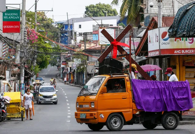 Catholic church staff riding a truck take a wooden cross around a quarantined community to mark Good Friday in Quezon City, Metro Manila, Philippines, 10 April 2020. The Catholic Bishops' Conference of the Philippines (CBCP) has encouraged the public to stay home during Holy Week and follow religious activities on radio, television or online to contain the spread of the coronavirus SARS-CoV-2, which causes the COVID-19 disease. (Photo by Rolex Dela Pena/EPA/EFE)