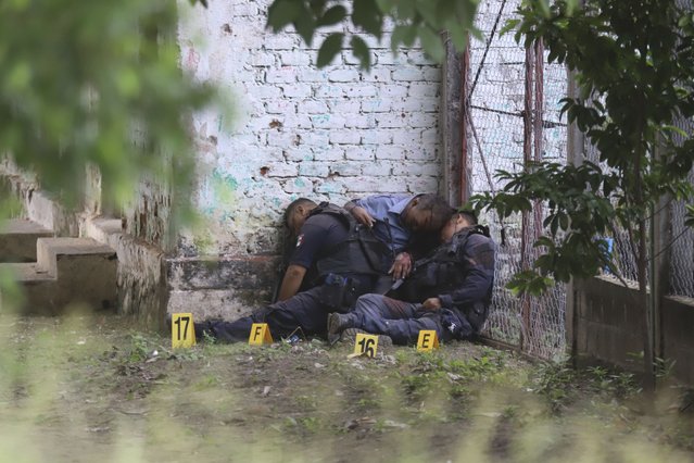 The bodies of slain police officers are slumped against a wall in El Papayo, Coyuca de Benitez municipality, Guerrero state, Mexico, Monday, October 23, 2023. Twelve police officers and their boss were gunned down on Monday, according to Guerrero state prosecutor's office. (Photo by Bernardino Hernandez/AP Photo)
