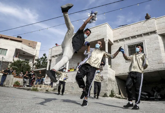 Dancers of the Palestinian Jafra Dabke Team perform a traditional dabke dance while wearing latex gloves and surgical masks for people confined due to a COVID-19 coronavirus pandemic lockdown in the village of Tarqumia northwest of Hebron in the occupied West Bank, on April 15, 2020. (Photo by Hazem Bader/AFP Photo)