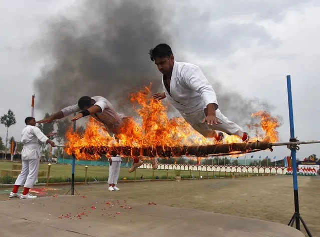 India's Central Reserve Police Force (CRPF) personnel perform a stunt during the passing out parade in Humhama, on the outskirts of Srinagar August 28, 2014. According to authorities from CRPF, 368 new policemen were formally inducted into the force after completing a 44-week rigorous training course and will be deployed in different parts of India. (Photo by Danish Ismail/Reuters)