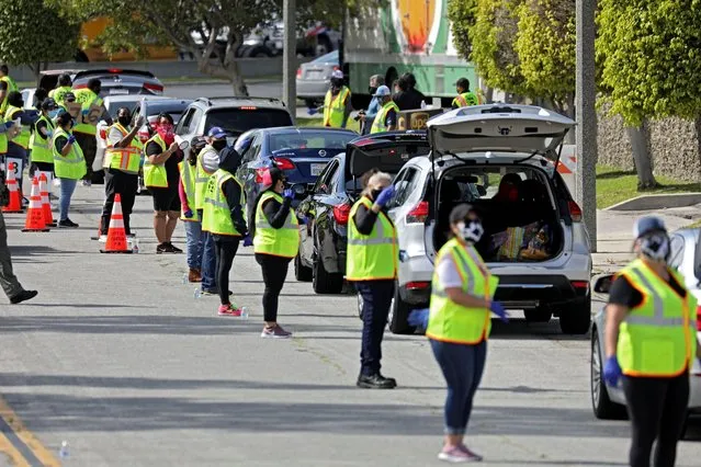 Volunteers control traffic flow as households receive boxes of food at a drive-thru food distribution site from the Los Angeles Regional Food Bank and Los Angeles County Federation of Labor as authorities encourage social distancing to prevent the spread of coronavirus disease (COVID-19) outside the Teamsters Local 572 office in Carson, California, U.S., April 18, 2020. (Photo by Patrick T. Fallon/Reuters)