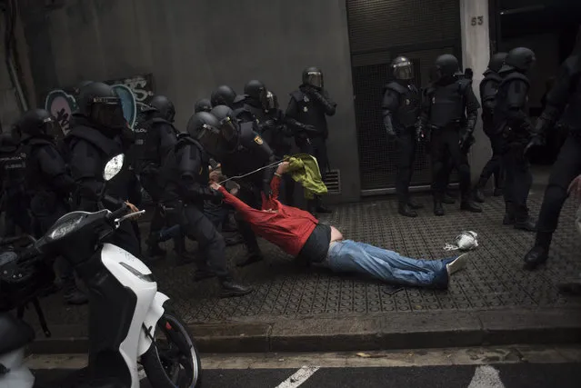 Riot police drag a member of the public away from a school being used as a polling station for the banned referendum, in Barcelona, Spain, on Sunday, October 1, 2017. Spanish police moved in to shut down some polling stations as voting began Sunday in Catalonias illegal referendum on independence. (Photo by Geraldine Hope Ghelli/Bloomberg via Getty Images)