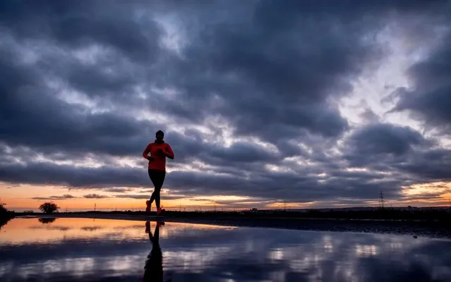 A woman runs on a small road before sunrise in Frankfurt, Germany, early Monday, March 2, 2020. (Photo by Michael Probst/AP Photo)
