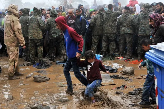 Migrants and refugees wait in the mud and under the rain to cross the Greek-Macedonian border near the village of Idomeni, in northern Greece on September 10, 2015. (Photo by Sakis Mitrolidis/AFP Photo)