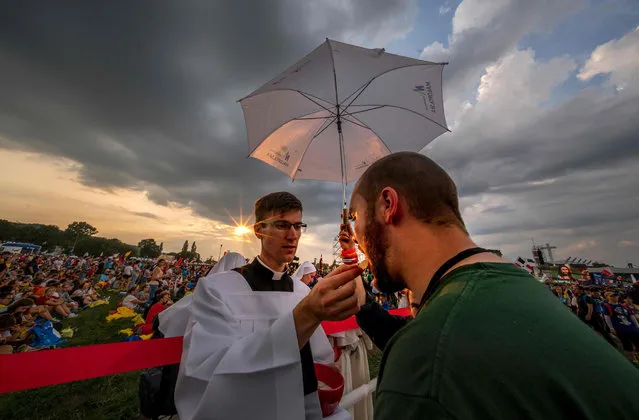 A priest gives a holy communion to a pilgrim during the Opening Mass on the first day of the World Youth Days in Krakow, on July 26, 2016. Pope Francis heads to Poland Wednesday for an international Catholic youth festival with a mission to encourage openness to migrants made tougher by a fresh jihadist attack in France which has spooked and saddened pilgrims. (Photo by Joe Klamar/AFP Photo)