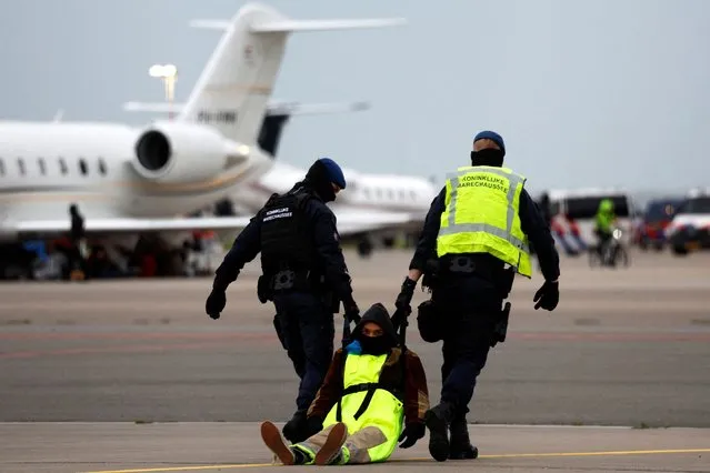 Police officers detain a climate activist during a protest against environmental pollution from aviation, at Amsterdam's Schiphol Airport, in Schiphol, Netherlands on November 5, 2022. (Photo by Piroschka van de Wouw/Reuters)