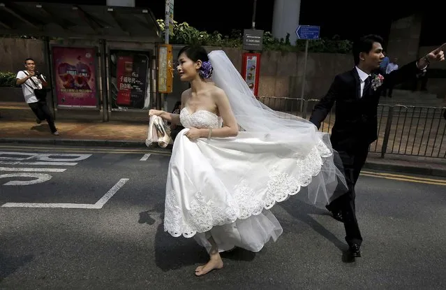 A couple, running late for their wedding ceremony due to the occupation of the main roads by pro-democracy protesters, run towards the marriage registry, in the central business district of Hong Kong Tuesday, October 14, 2014. Hong Kong police removed some barricades on Tuesday from the edge of pro-democracy protest zones that have choked off roads for weeks, the second straight day they have taken such action and signaling their growing impatience with the student-led demonstrators. (Photo by Vincent Yu/AP Photo)