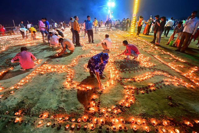 Devotees light traditional oil lamps as they celebrate the Hindu festival of “Dev Deepawali” at Sangam, the confluence of the rivers Ganges, Yamuna and mythical Saraswati in Prayagraj on November 7, 2022. (Photo by Sanjay Kanojia/AFP Photo)