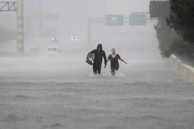 George Cochrum and Caroline Wheeler walk down a flooded section of Interstate 610 in floodwaters from Tropical Storm Harvey on August 27, 2017, in Houston, Texas. (Photo by David J. Phillip/AP Photo)
