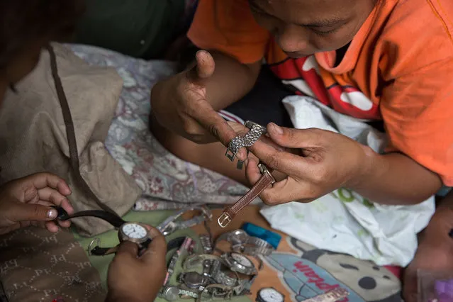 A Thai woman and her young son examine watches to see if they can be resold in their home in a disused airplane on September 12, 2015 in Bangkok, Thailand. (Photo by Taylor Weidman/Getty Images)