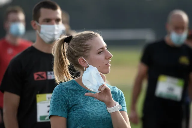 A runner removes her protective face mask at the start of the "Tour du Pays de Vaud" running stage race organised with health measures amid the COVID-19 outbreak, caused by the novel coronavirus, on August 12, 2020 in Champvent. Switzerland announced on August 12, 2020 that with COVID-19 cases rising again, it was prolonging the ban on gatherings of more than 1,000 people until October 1, triggering upheaval for major sports. (Photo by Fabrice Coffrini/AFP Photo)