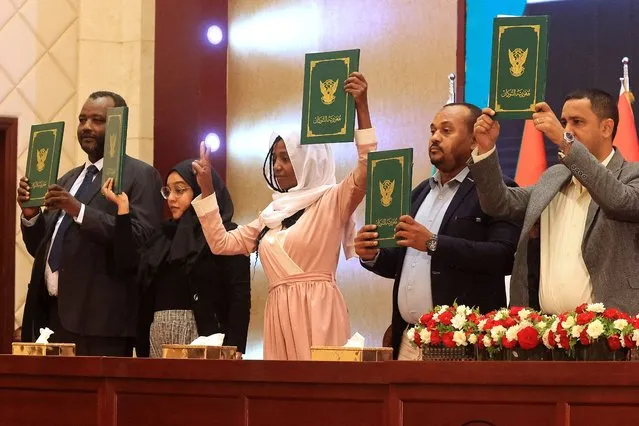 Sudanese civilian leaders lift documents following the signature of an initial deal with military powers aimed at ending a deep crisis caused by last year's military coup, in the capital Khartoum on December 5, 2022. The past year has seen near-weekly protests and a crackdown that pro-democracy medics say has killed at least 121, a spiralling economic crisis exacerbated by donors slashing funding, and a resurgence of ethnic violence in several remote regions. Divisions among civilian groups have deepened since the coup, with some urging a deal with the military while others insist on “no partnership, no negotiation”. (Photo by Ashraf Shazly/AFP Photo)