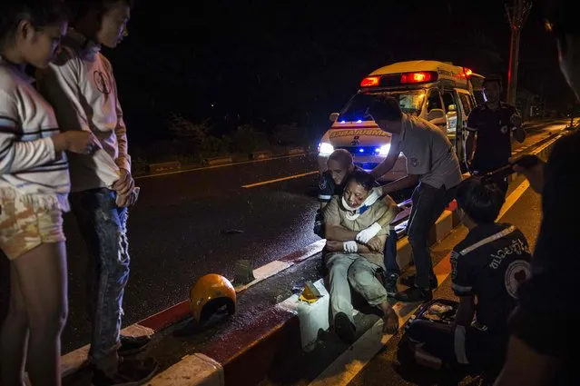 This picture taken on May 29, 2016 shows Vientiane Rescue volunteers helping an injured motorcycle driver following an accident under the influence of alcohol in Vientiane, Laos. Founded in 2010 by a group of foreigners, “Vientiane Rescue” is a much needed lifeline for those in need of urgent medical care where poorly maintained roads, dilapidated vehicles, an increase in motorcycle use and the widespread prevalence of drink driving makes Vientiane one of Asia's most precarious capitals for road deaths. (Photo by Lillian Suwanrumpha/AFP Photo)