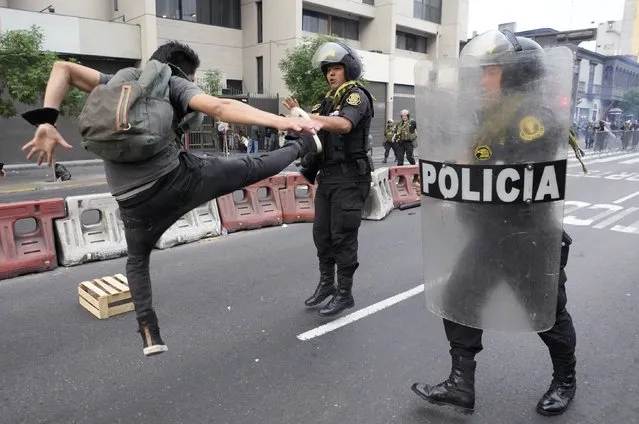 A supporter of ousted President Pedro Castillo jump kicks at a police officer during a protest in Lima, Peru, Thursday, December 8, 2022. Peru's Congress voted to remove Castillo from office Wednesday and replace him with the vice president, shortly after Castillo tried to dissolve the legislature ahead of a scheduled vote to remove him. (Photo by Fernando Vergara/AP Photo)