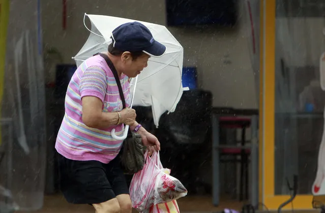 A woman struggles with her umbrella against powerful gusts of wind generated by typhoon Megi across the the island in Taipei, Taiwan, Tuesday, September 27, 2016. (Photo by Chiang Ying-ying/AP Photo)