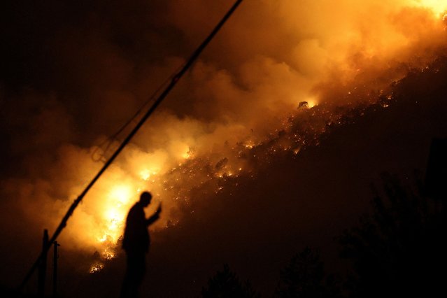 A member of emergency services stands next to a wildfire near Bulqiza, Albania, on July 26, 2025. (Photo by Florion Goga/Reuters)