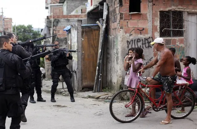Residents react as policemen take up position during an operation in the Mare slums complex of Rio de Janeiro, in this March 26, 2014 file photo. (Photo by Ricardo Moraes/Reuters)
