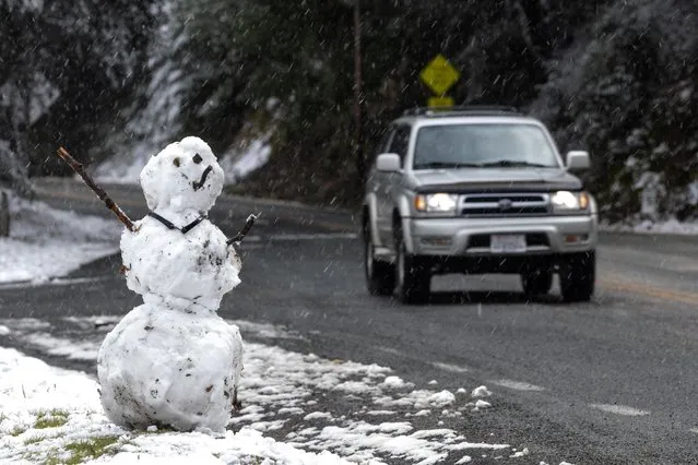 A snowman is seen by the side of a road as snow falls on the hills around the Bay Area while a massive winter storm passes along the west coast, delivering some snow, freezing rains, and gusty winds around, near San Jose, California, U.S., February 23, 2023. (Photo by Carlos Barria/Reuters)