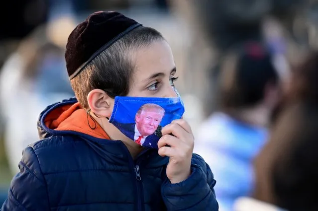 A child wears a protective face mask depicting U.S. President Donald Trump at the 2020 annual National Chanukah Menorah Lighting to mark the First Night of Chanukah near the White House in Washington, U.S., December 10, 2020. (Photo by Erin Scott/Reuters)