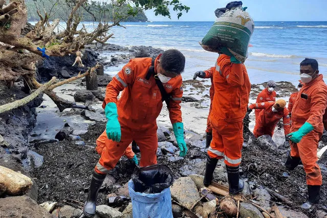 This handout photo taken on March 8, 2023 and released by the Philippine Coast Guard (PCG) shows coast guard personnel and volunteers collecting debris covered with oil during a clean-up along the coast in Pola, Oriental Mindoro Province, days after an oil spill from a sunken tanker. (Photo by Handout/Philippine Coast Guard (PCG) via AFP Photo)