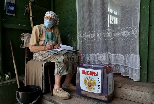 A local resident fills in documents near a mobile ballot box outside her house during a seven-day vote on constitutional reforms, in the village of Troitskoye in Moscow region, Russia on June 25, 2020. (Photo by Evgenia Novozhenina/Reuters)
