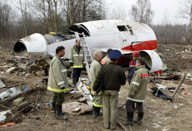In this April 13, 2010 file photo, emergency ministry workers stand near the wreckage at the site of the plane crash that killed Polish President Lech Kaczynski in Smolensk, western Russia. Poland's government is accusing European Council President Donald Tusk of betraying national interests and bowing to Moscow in the investigation of the 2010 plane crash in Russia that killed Kaczynski and 95 others. (Photo by Mikhail Metzel/AP Photo)